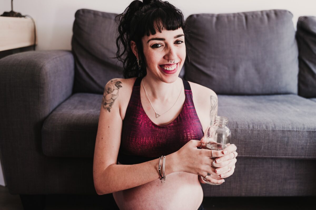 young pregnant woman at home practicing yoga sport and drinking water, healthy lifestyle